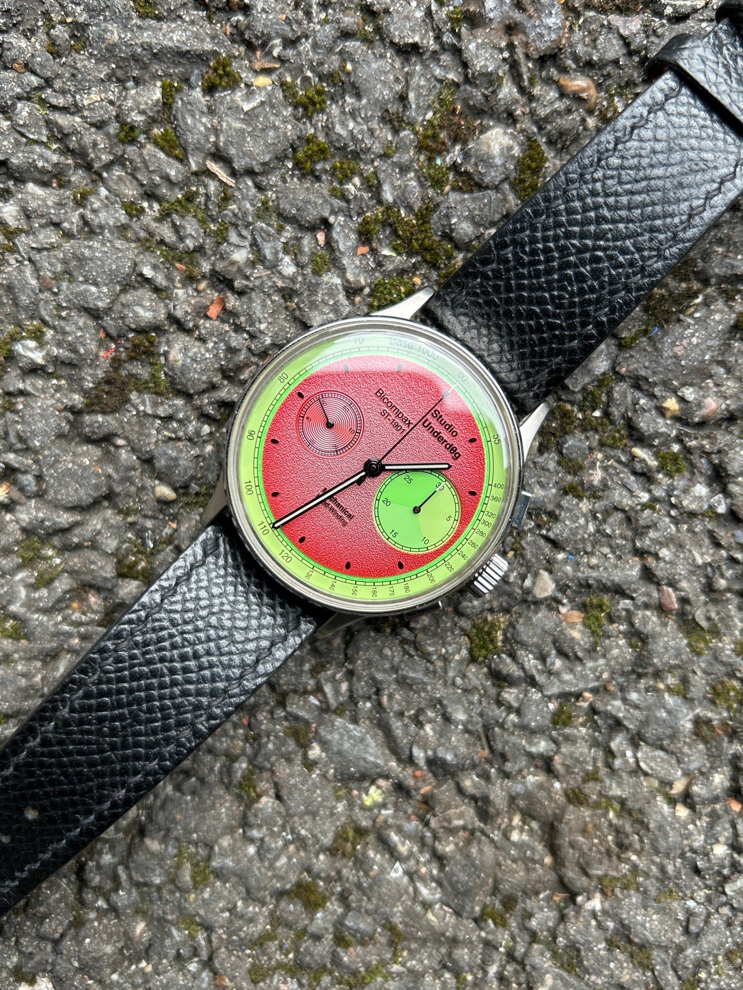 Wristwatch with a unique red and green face on a textured surface