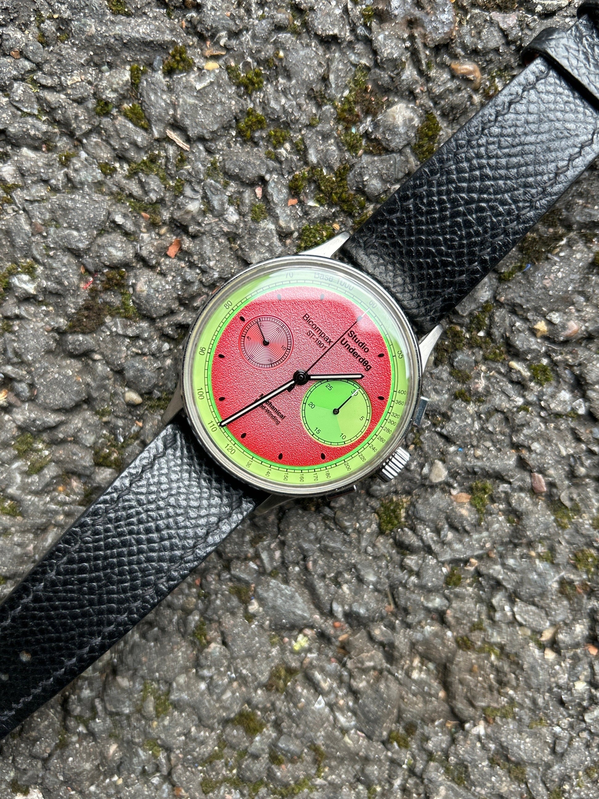 Wristwatch with a unique red and green face on a textured surface